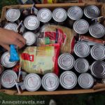 Packing a box full of cans and spaghetti for vacation.