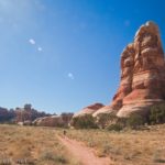 Hiker on a trail below a rock spire in Chesler Park, Canyonlands National Park, Utah