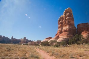 Hiker on a trail below a rock spire in Chesler Park, Canyonlands National Park, Utah