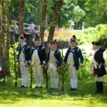 Soldiers stand with their muskets along the river waiting for the Declaration of Independence to be read at North Bridge, Minute Man National Historical Park, Massachusetts