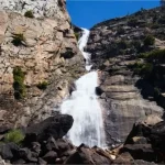 A waterfall tumbles in two tiers down rocks