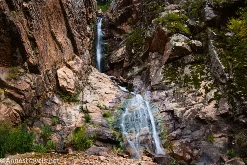 A waterfall tumbles in two stages down a cliff face