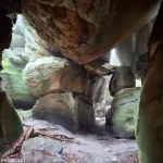 Rocks with moss above and around a sandy dirt floor