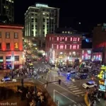 A city street intersection surrounded by lit up buildings