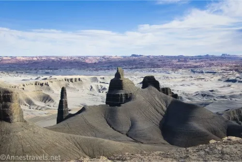 Fantastic dark formations in front of lighter desert with distant mountains under clouds in a blue sky