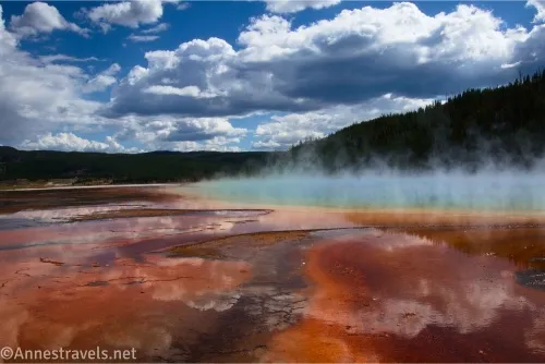 Colorful drainage channels and spring at the Grand Prismatic Spring below puffy white clouds in Yellowstone National Park