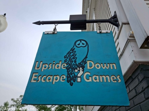 Turquoise sign with an owl and the words Upside Down Escape Games